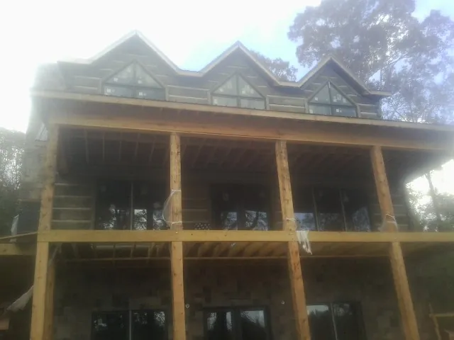 Dormers and porch framing on a large log home under construction — Roof Coating work by our crew in Turtletown