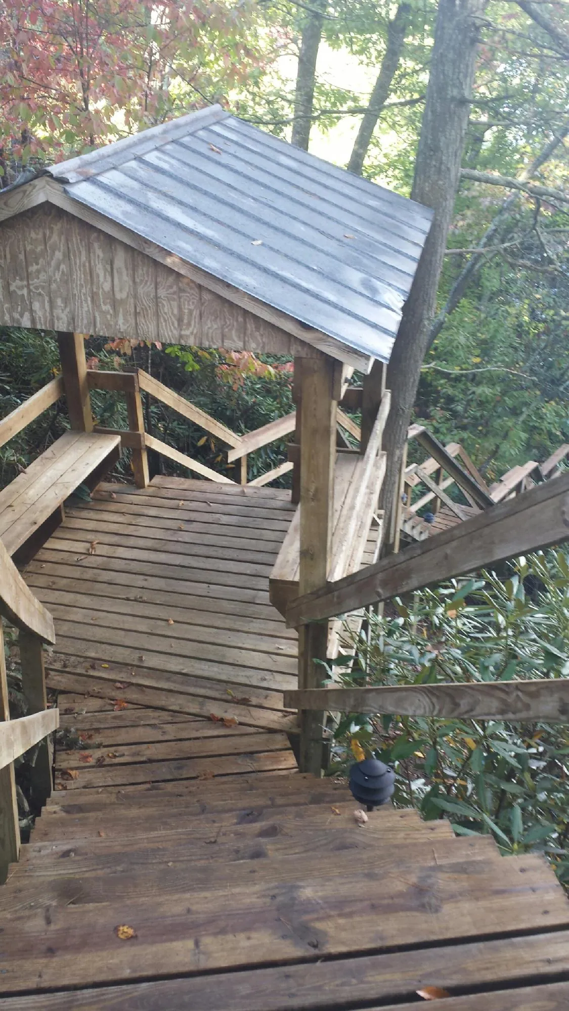 Metal roofed shelter over wooden steps on a wooded walkway — Skylight Repair & Installation work by our crew in Turtletown