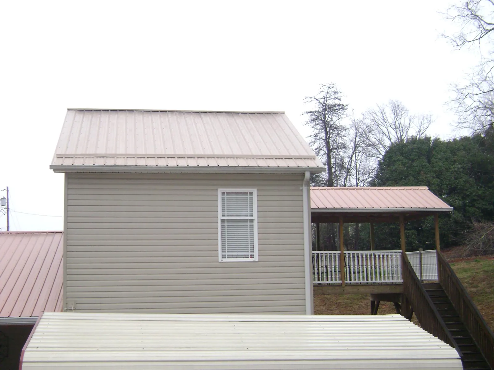 Tan metal roofs on a two story addition and attached porch, from a Roof Replacement job in Turtletown