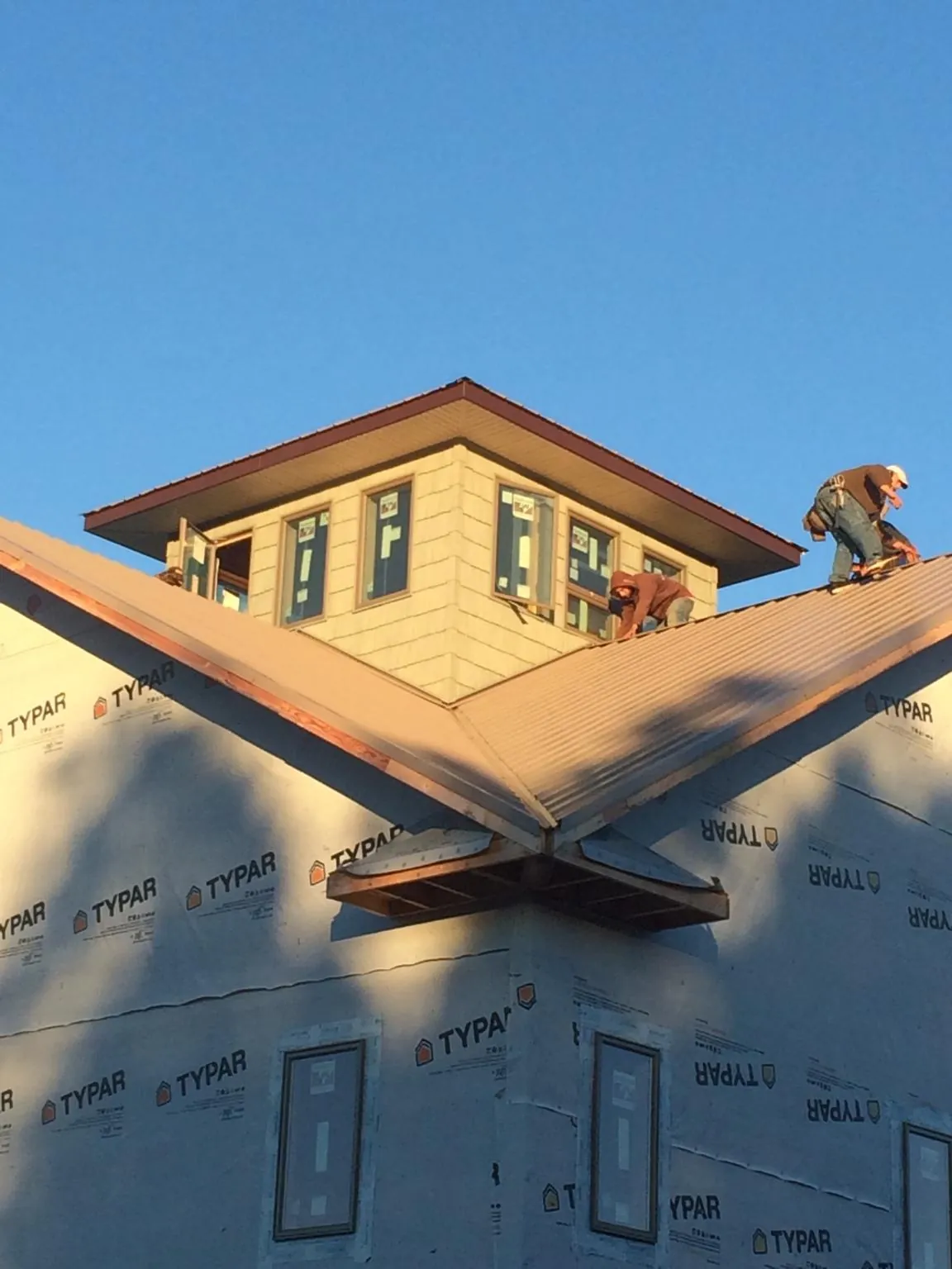 Roofers working around a rooftop cupola on a new metal roof at sunset — Roof Waterproofing in Turtletown by Roofing Brothers